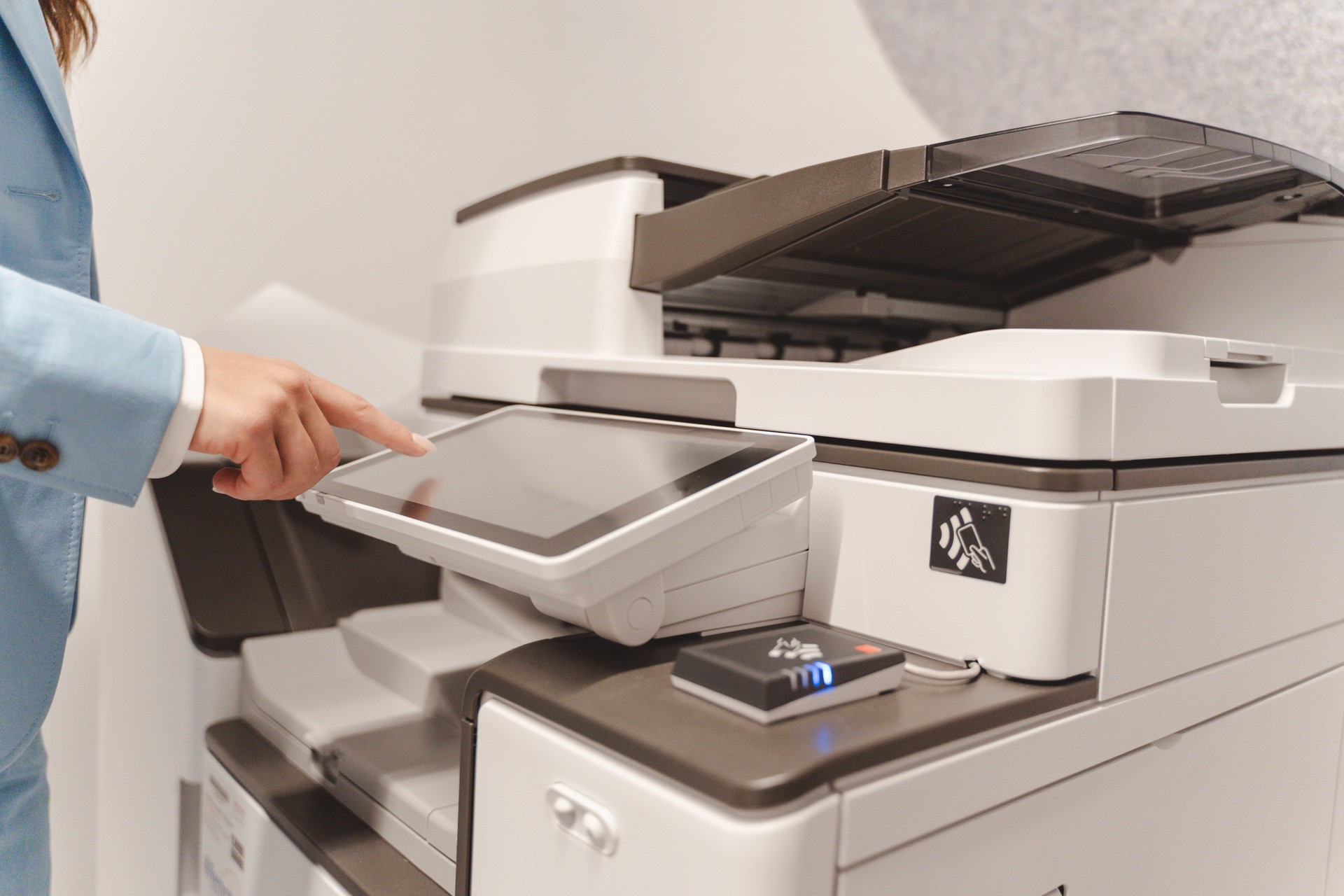 Businesswoman using touchscreen of modern multifunction printer in office